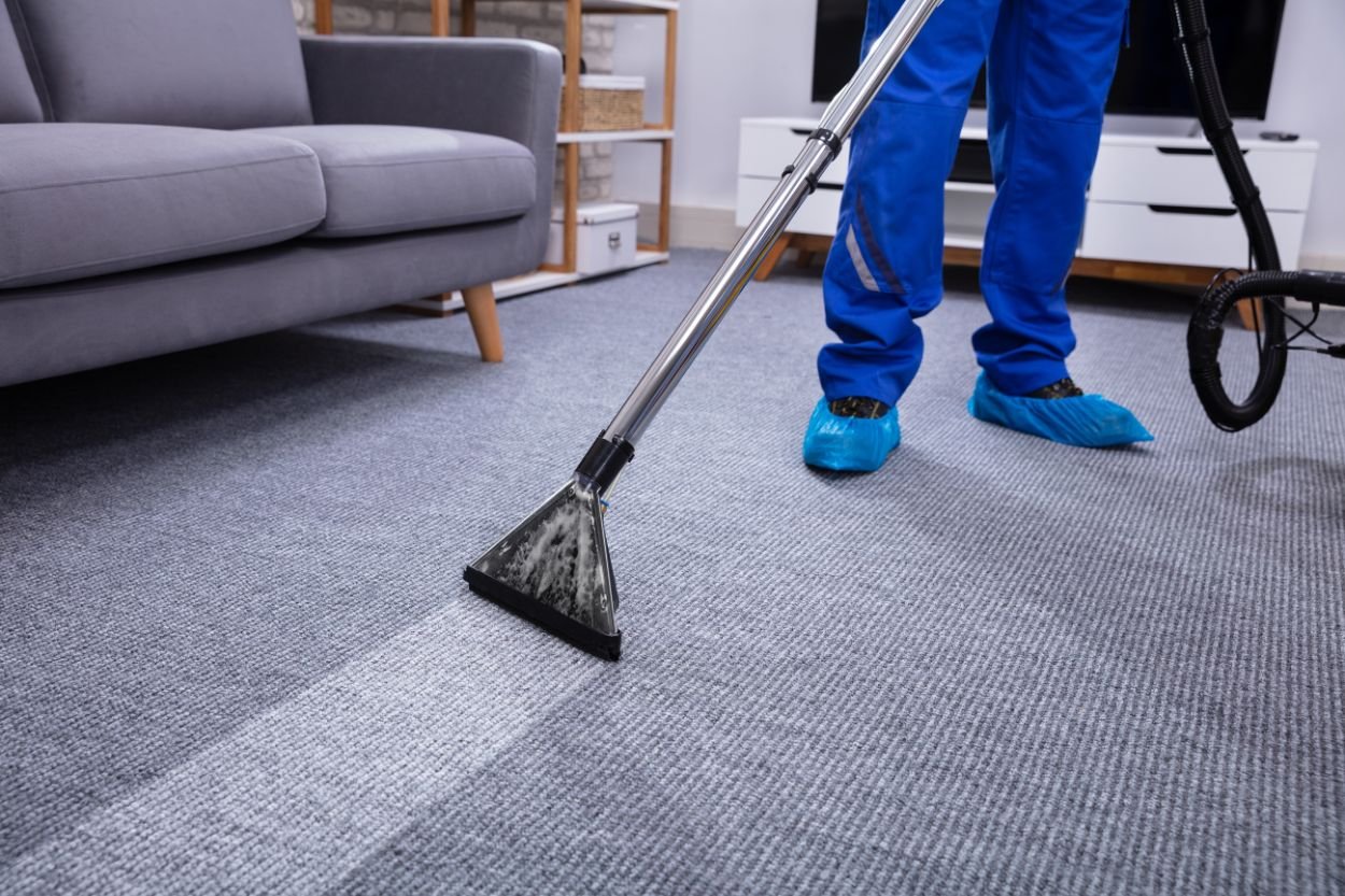 A man in blue overalls actively cleans a carpet, showcasing a mold removal service located in Honolulu, HI.