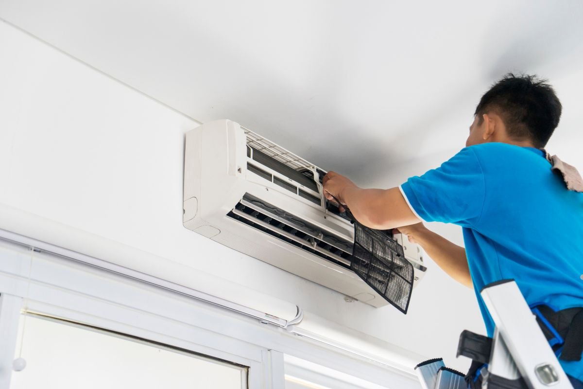 A man replaces an air filter in an air conditioner to prevent mold growth. 
