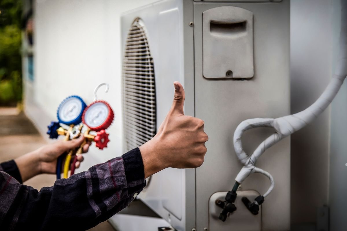 A man points to an air conditioner while holding a thermometer, emphasizing the importance of indoor air quality and HVAC systems.